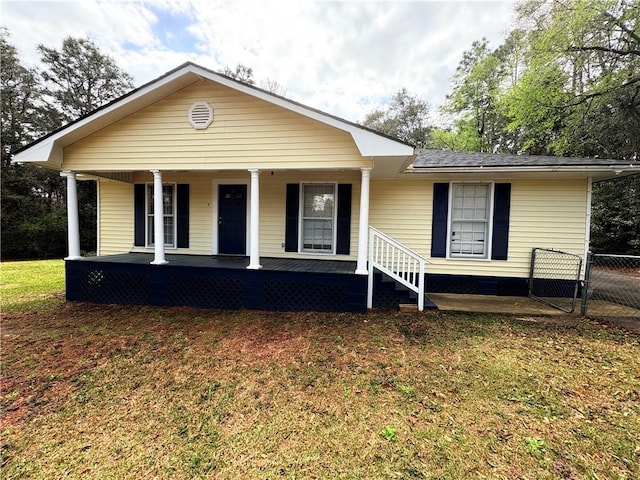 view of front of house featuring covered porch, a front yard, and fence