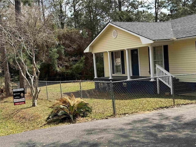 view of front of home with a fenced front yard, covered porch, a front lawn, and a shingled roof