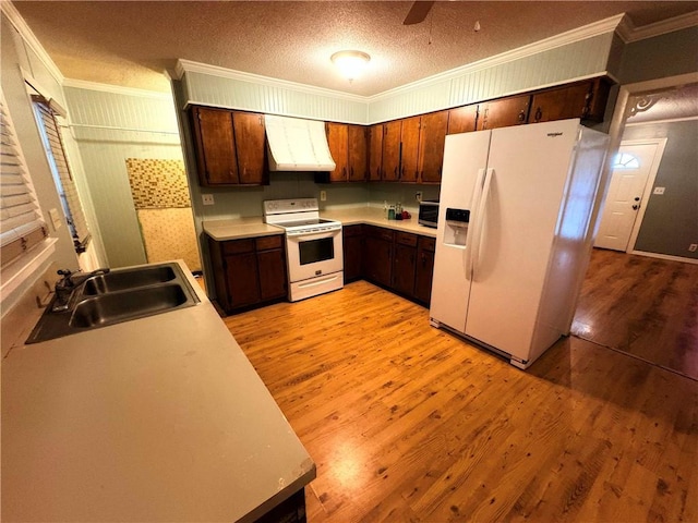 kitchen with ventilation hood, light wood-type flooring, light countertops, white appliances, and a sink