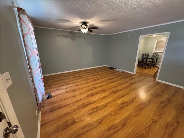 unfurnished bedroom with crown molding, ceiling fan, baseboards, wood finished floors, and a textured ceiling