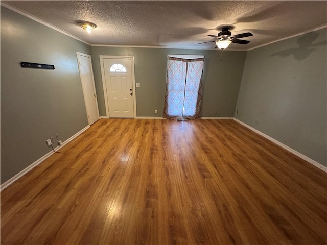 entrance foyer featuring baseboards, crown molding, ceiling fan, and wood finished floors