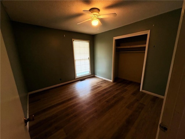 unfurnished bedroom featuring a closet, ceiling fan, baseboards, and dark wood-style flooring