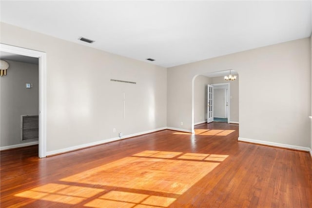 spare room with hardwood / wood-style flooring and a notable chandelier