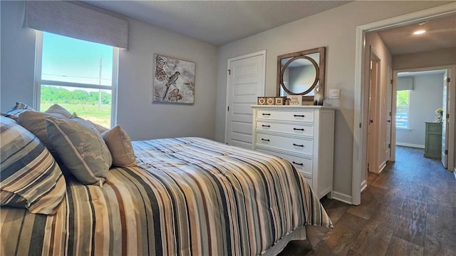 bedroom with dark hardwood / wood-style floors and multiple windows