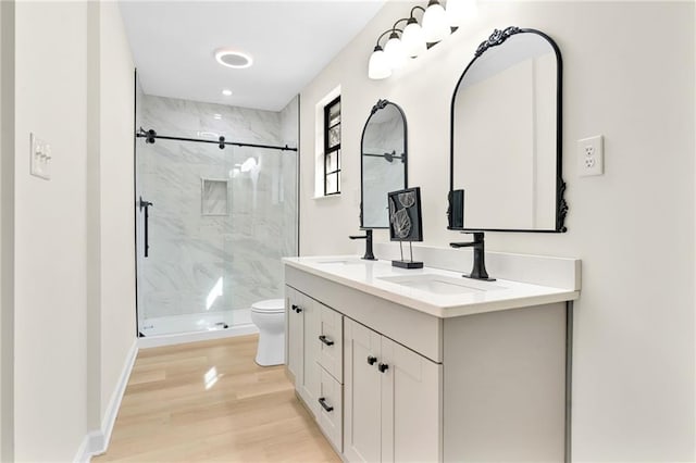 bathroom with a shower with door, vanity, hardwood / wood-style floors, and toilet