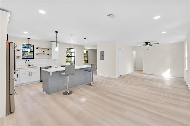 kitchen featuring decorative light fixtures, a kitchen breakfast bar, a kitchen island, stainless steel appliances, and white cabinets