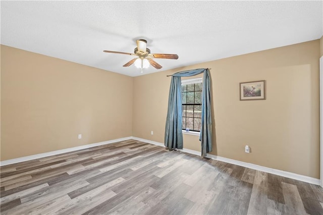 spare room with a textured ceiling, wood finished floors, a ceiling fan, and baseboards