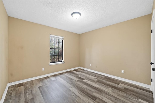 spare room with a textured ceiling, baseboards, and wood finished floors