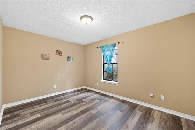 empty room featuring dark wood-type flooring, a textured ceiling, and baseboards