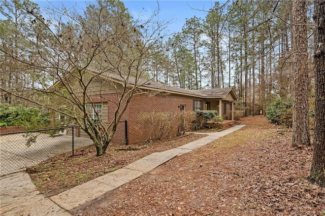 view of home's exterior featuring brick siding and fence