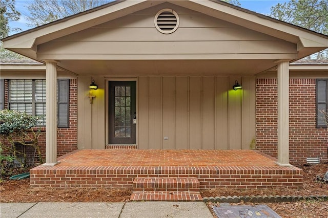 view of exterior entry with a porch and brick siding