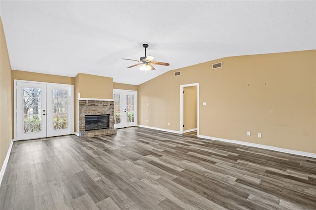 unfurnished living room with baseboards, visible vents, vaulted ceiling, french doors, and a fireplace