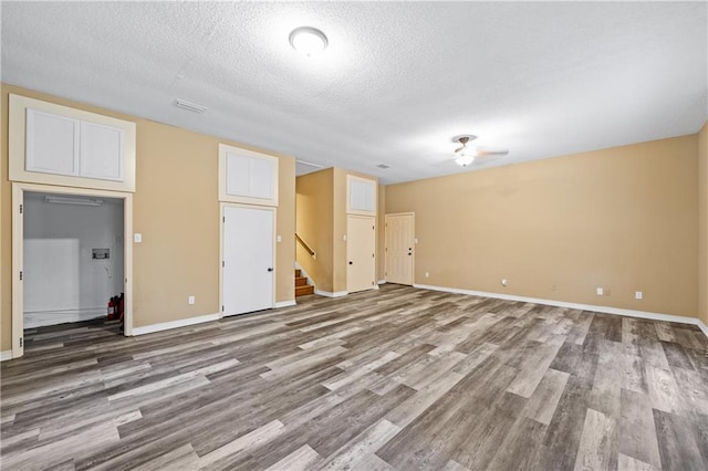 spare room featuring baseboards, visible vents, wood finished floors, stairs, and a textured ceiling