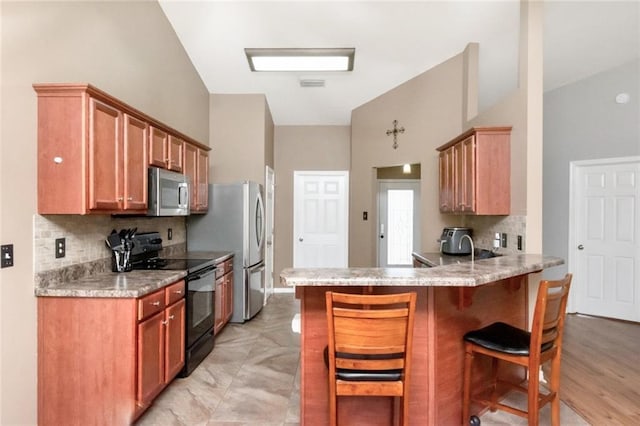 10234 Scott Plantation Dr N, Mobile, AL 36695 - kitchen featuring appliances with stainless steel finishes, decorative backsplash, a kitchen bar, a peninsula, and light countertops