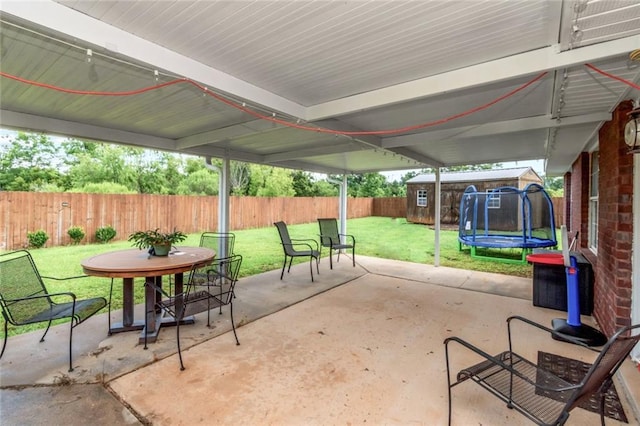 10234 Scott Plantation Dr N, Mobile, AL 36695 - fenced backyard featuring a trampoline, a patio, a storage shed, and outdoor dining area
