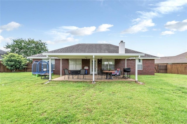 10234 Scott Plantation Dr N, Mobile, AL 36695 - back of house with a trampoline, a patio, a fenced backyard, brick siding, and a chimney