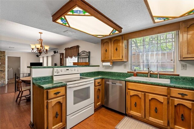 kitchen featuring stainless steel dishwasher, white range with electric cooktop, a peninsula, a sink, and brown cabinets