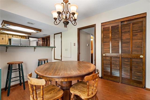 dining area with baseboards, wood finished floors, a notable chandelier, and visible vents