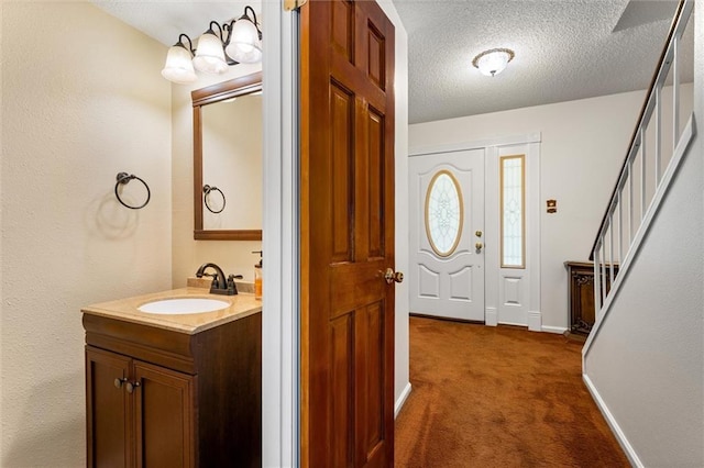 bathroom with a textured ceiling, vanity, and baseboards