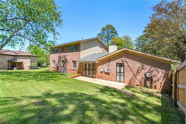 rear view of house featuring central AC unit, a yard, a chimney, a patio, and brick siding