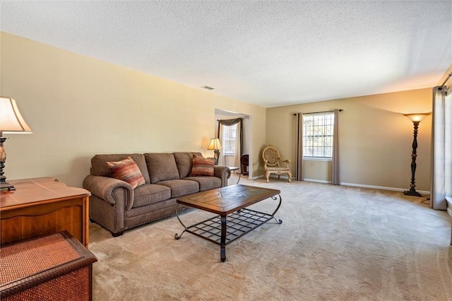 living area featuring light carpet, baseboards, visible vents, and a textured ceiling