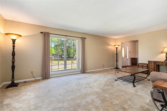 carpeted living area featuring a textured ceiling and baseboards