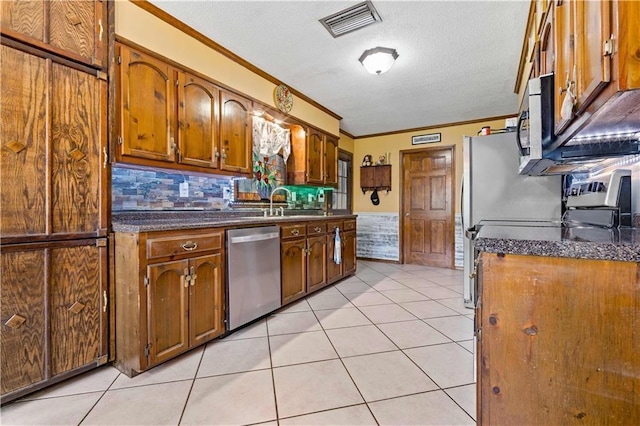 kitchen with visible vents, dark countertops, stainless steel appliances, and ornamental molding