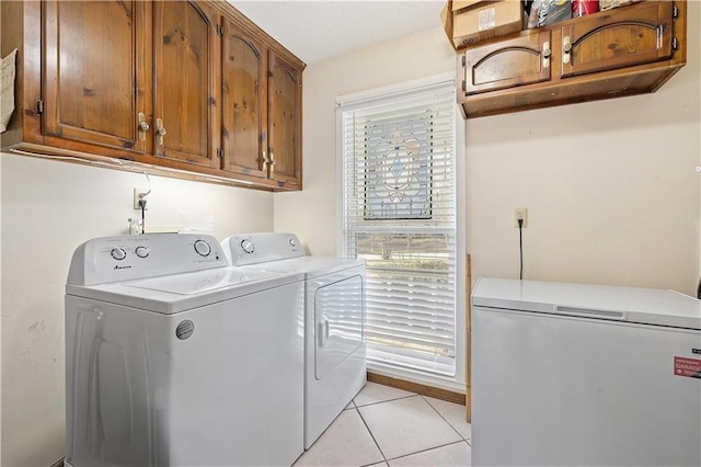 laundry room featuring light tile patterned floors, cabinet space, and washing machine and clothes dryer