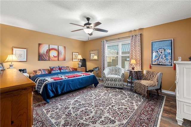 bedroom with a textured ceiling, wood finished floors, ceiling fan, and baseboards