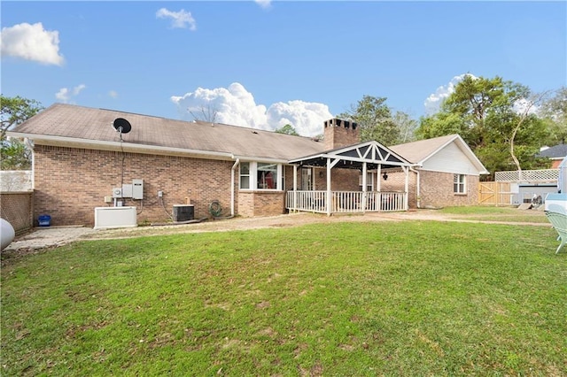 back of property featuring a lawn, fence, central AC unit, and brick siding