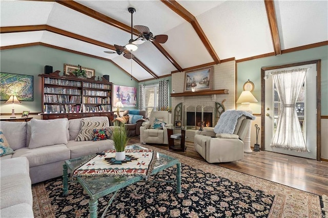 living room featuring vaulted ceiling with beams, a ceiling fan, wood finished floors, and a fireplace
