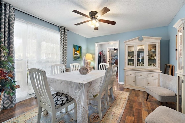 dining space with a textured ceiling, ceiling fan, and dark wood finished floors