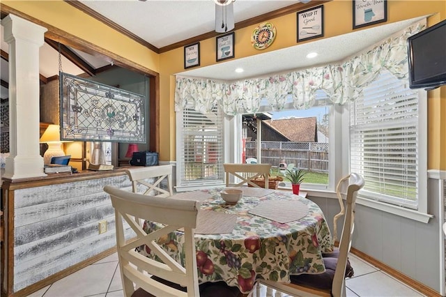 dining space featuring ornamental molding, a healthy amount of sunlight, tile patterned floors, and ornate columns