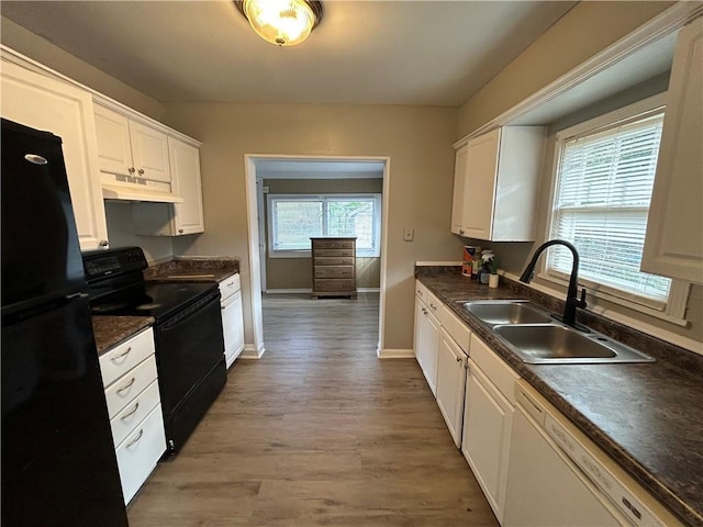 kitchen featuring light wood-type flooring, a healthy amount of sunlight, sink, black appliances, and white cabinetry