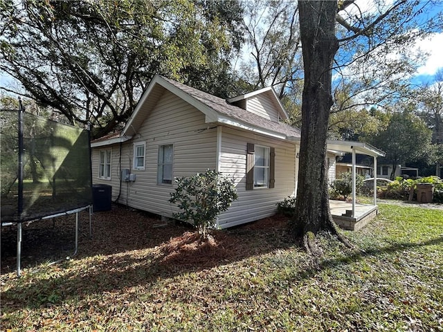 view of property exterior featuring a lawn, central AC, and a trampoline