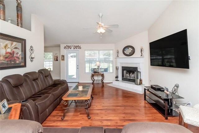 living room featuring ceiling fan, a tile fireplace, and wood-type flooring