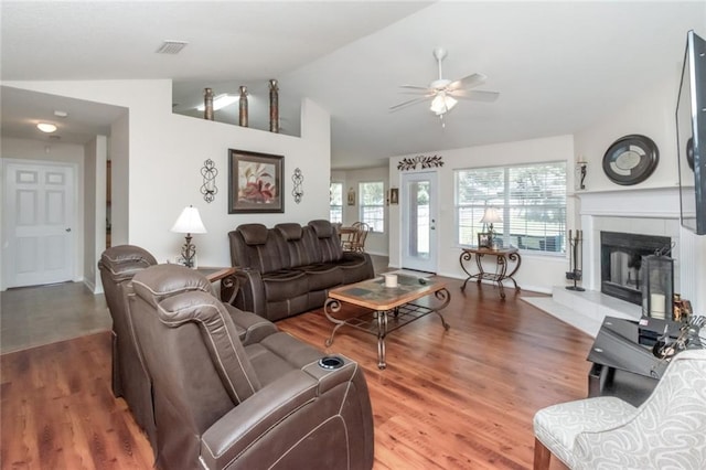 tiled living room featuring ceiling fan, a fireplace, and lofted ceiling