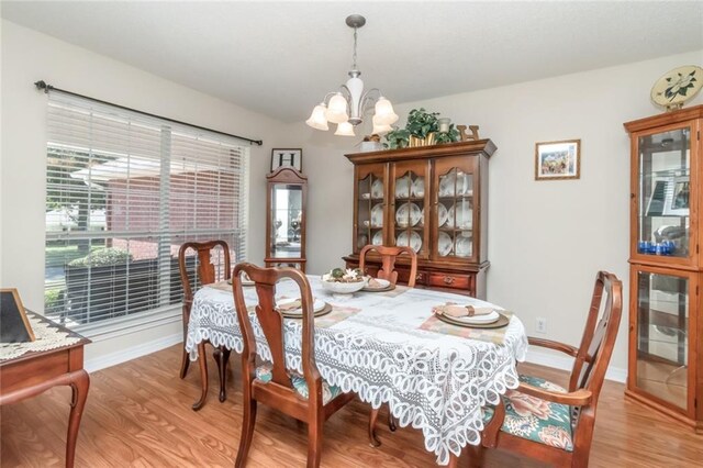 dining space featuring light hardwood / wood-style floors and an inviting chandelier