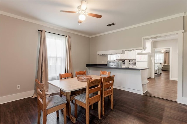 dining space with ceiling fan, ornamental molding, a wealth of natural light, and dark hardwood / wood-style floors