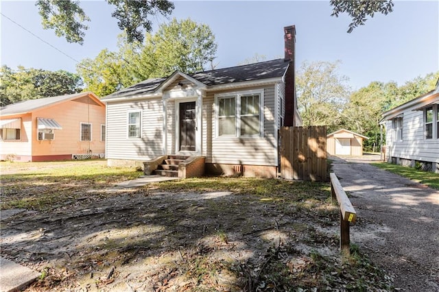 bungalow-style house featuring cooling unit and a shed