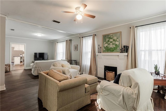 living room with ceiling fan, crown molding, dark hardwood / wood-style flooring, and a fireplace