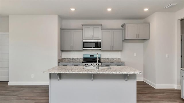 9836 Nadine Ln S, Mobile, AL 36695 - kitchen featuring gray cabinets, stainless steel stove, dark wood-type flooring, a center island with sink, and light stone counters