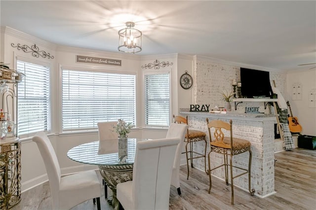 dining space featuring a fireplace, crown molding, an inviting chandelier, and light hardwood / wood-style floors