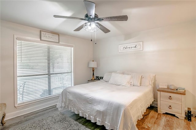 bedroom featuring multiple windows, hardwood / wood-style flooring, and ceiling fan