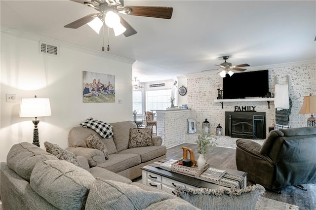 living room with ornamental molding, a brick fireplace, wood-type flooring, and ceiling fan