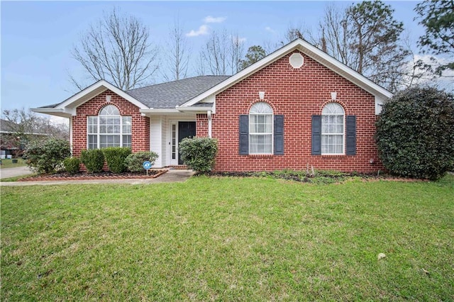 ranch-style home with a shingled roof, a front lawn, and brick siding