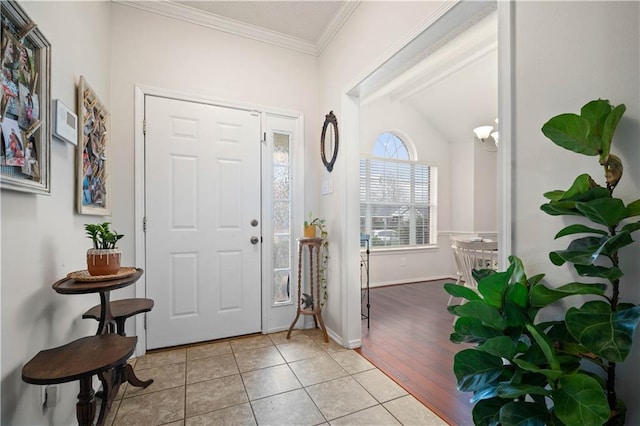 foyer featuring light tile patterned floors, baseboards, and crown molding