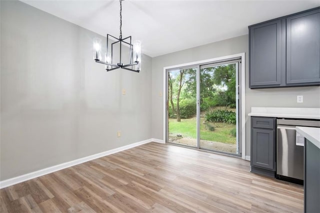 unfurnished dining area with light wood-type flooring, baseboards, and an inviting chandelier