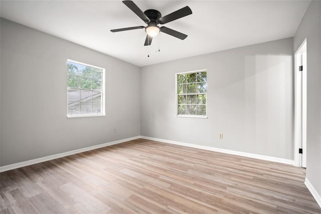 empty room with light wood finished floors, a ceiling fan, baseboards, and a wealth of natural light