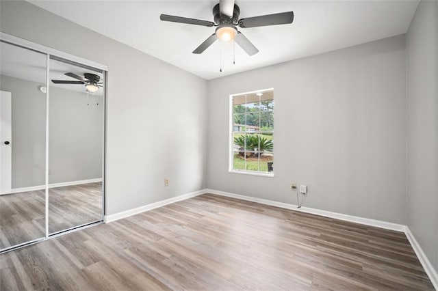 unfurnished bedroom featuring a closet, a ceiling fan, baseboards, and wood finished floors